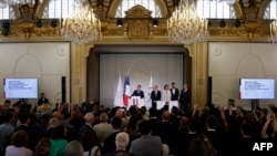 France's President Emmanuel Macron gives a speech next to International Olympic Committee (IOC) President Thomas Bach and others during a reception for international journalists accredited for the Paris 2024 Olympic Games, July 22, 2024. 