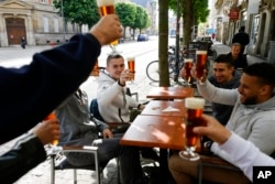 FILE - People toast each other at a cafe terrace May, 19, 2021, in Strasbourg, eastern France.