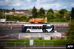 Pengemudi Stuart Doidge memantau bus otonom (swakemudi) CAVForth, AB1, yang melaju melintasi Forth Road Bridge antara Edinburgh dan Fife, saat dipamerkan kepada pers di Queensferry, Skotlandia, 11 Mei 2023. (Andy Buchanan / AFP)