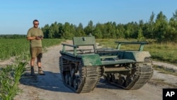 Andrii Denysenko, CEO of design and production bureau "UkrPrototyp," stands by Odyssey, an 800-kilogram ground drone prototype, at a corn field in northern Ukraine, June 28, 2024.