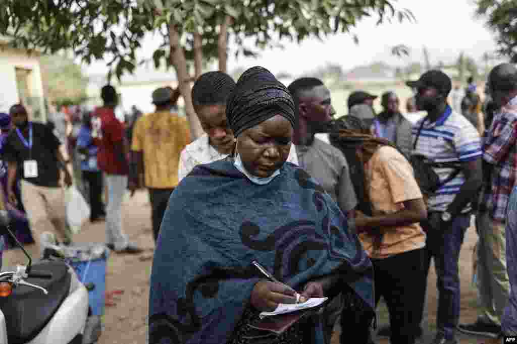 A woman writes her name on a unofficial voters list as people wait for election material to arrive at a polling station in Abuja on February 25, 2023.&nbsp;