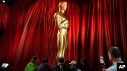 Workers move an Oscar statue during preparations for Sunday's 95th Academy Awards, March 11, 2023, in Los Angeles. 