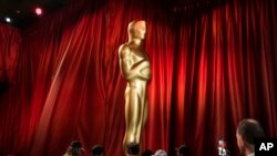 Workers move an Oscar statue during preparations for Sunday's 95th Academy Awards, March 11, 2023, in Los Angeles. 