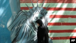 FILE - A woman walks past a satirized painting of the Statue of Liberty on the wall of the former U.S. Embassy, in Tehran, April 24, 2008. An Iranian court on Oct. 26, 2023, told the U.S. government to compensate victims of a failed 1980 hostage rescue effort at the embassy. 