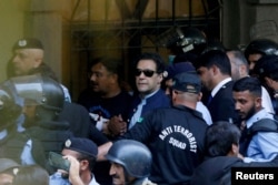 FILE - Security officers escort Pakistani former Prime Minister Imran Khan as he appears in Islamabad High Court, in Islamabad, Pakistan, May 12, 2023.