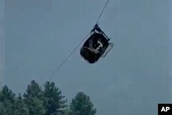 In this image taken from video, a cable car carrying seven children and one adult dangles hundreds of meters above the ground in the remote Battagram district, Khyber Pakhtunkhwa, Pakistan, Aug. 22, 2023.