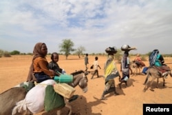 FILE - Sudanese families fleeing the conflict in Sudan's Darfur region make their way through the desert after crossing the border between Sudan and Chad to seek refuge in Goungour, Chad, May 12, 2023.