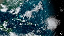 This satellite image provided by the U.S. National Oceanographic and Atmospheric Administration shows Hurricane Lee, right, in the Atlantic Ocean, Sept. 8, 2023. (NOAA via AP)