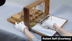 Photo shows how President Thomas Jefferson may have used a polygraph. Holding the left pen in the right hand, the operator presses the paper ejection knob with the left hand to pull out new paper.