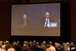 Shareholders watch Warren Buffett and Charlie Munger from the overflow room during the Berkshire Hathaway annual meeting, in Omaha, Neb., May 6, 2023.