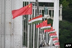 Bendera nasional China dan Hongaria menghiasi Jembatan Erzsebet di Budapest, Hongaria, 8 Mei 2024, menjelang kunjungan Presiden China Xi Jinping. (Attila KISBENEDEK / AFP)