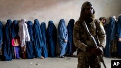 Talibanski borac stoji na straži dok žene čekaju da dobiju obroke hrane koje dijeli grupa humanitarne pomoći, u Kabulu, Afganistan, 23. maja 2023. (AP Photo/Ebrahim Noroozi)