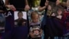 (FILE) A girl holds a photo of a Ukrainian POW killed in 2022 in Olenivka, eastern Ukraine, during a memorial in Kyiv on July 29, 2023.