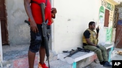 FILE - Jimmy Chérizier, right, better known as Barbecue, and the leader of the 'G9 and Family' gang, speaks into his cellphone in the Delmas 6 neighborhood of Port-au-Prince, Haiti, March 5, 2024.