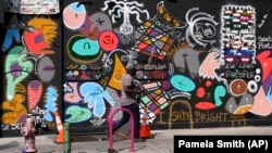 A man walks past a mural in the Harlem neighborhood of New York, Thursday, Aug. 15, 2024. (AP Photo/Pamela Smith)