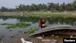 Construction worker Somej Mia repairs his boat on the bank of the Bangshai River, upstream of the Buriganga River, in the Mirzapur area of Tangail, Bangladesh, March 1, 2023.