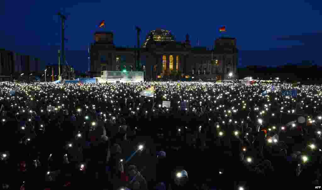 Учесниците ги вклучуваат со своите мобилни телефони за време на демонстрациите против расизмот и политиката на крајната десница пред зградата на Рајхстагот во Берлин, Германија.