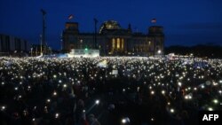 Participants light with their mobile phones during a demonstration against racism and far right politics in front of the Reichstag building in Berlin, Germany.