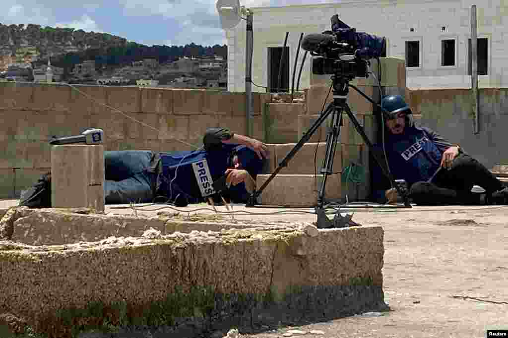 Палестински медиумски работници се штитат при пукање додека беа на покривот за да известуваат за израелски напад во Џенин, на Западниот Брег окупиран од Израел.