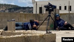 Palestinian journalists take cover while caught under fire on a rooftop while covering an Israeli raid in Jenin, in the Israeli-occupied West Bank.