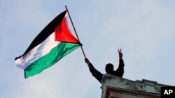 一名抗议人士在美国哥伦比亚大学汉密尔顿大厅的顶部挥舞一面巴勒斯坦旗帜。（2024年4月30日）