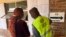 A Zimbabwe Electoral Commission official assists a voter in finding her name on a voter roll at a polling station in Harare, Aug. 24 2023. (Columbus Mavhunga/VOA)