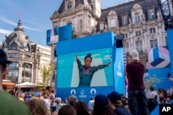 Spectators watch from a fan zone set up at the Hotel de Ville, the city hall, as Simone Biles of the United States performs on the vault during a women's artistic gymnastics qualification round at the 2024 Summer Olympics, July 28, 2024, in Paris.