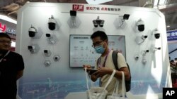 FILE - A visitor passes by security cameras on display at Security China 2023 in Beijing, June 7, 2023. Vendors showcased the latest in surveillance and public security technologies during the expo.