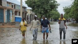 Men walk through floodwaters on a street in the town of Beledweyne, in Central Somalia on Monday, May 15, 2023.