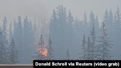 FILE - Flames and smoke rise from a wildfire visible from a highway in Jasper, Alberta, Canada, July 23, 2024, in this screen grab from a social media video. (Donald Schroll via Reuters)