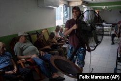 FILE - Aid worker Roger Duvan Lagunes carries a fan into an elderly shelter in Veracruz, Mexico, on June 16, 2024. (AP Photo/Felix Marquez)