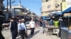 In this photo of Palestine Street in Hasaka, Syria, the government-controlled stores sit on the right and Kurdish-controlled stores sit on the left, March 22, 2024.