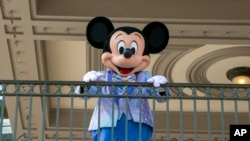 FILE - An actor dressed as Mickey Mouse greets visitors at the entrance to Magic Kingdom Park at Walt Disney World Resort, April 18, 2022, in Lake Buena Vista, Fla. 
