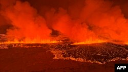 Asap mengepul dan lava yang mengalir mengubah langit menjadi oranye saat terjadi letusan gunung berapi di semenanjung Reykjanes tiga kilometer utara Grindavik, Islandia barat, 18 Desember 2023. (Penjaga Pantai Islandia / HANDOUT / AFP) 