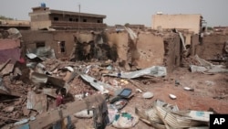 FILE - A man walks by a house hit in recent fighting in Khartoum, Sudan, April 25, 2023.