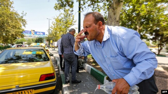 Bir adam, 11 Temmuz 2023'te Tahran'da sıcak hava dalgasında serinlemek için yüzünü şişedeki suyla duruluyor