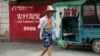 资料照：中国浙江桐庐一位农民走过淘宝的广告墙。（2015年7月20日）