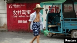 资料照：中国浙江桐庐一位农民走过淘宝的广告墙。（2015年7月20日）
