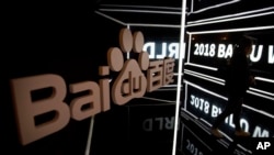ແຟ້ມພາບ - ຜູ້ເຂົ້າຮ່ວມງານຄົນນຶ່ງຍ່າງກາຍປ້າຍຈໍພາບຢູ່ທີ່ ກອງປະຊຸມລະດັບໂລກຂອງ Baidu World ໃນນະຄອນຫຼວງປັກກິ່ງ, ວັນທີ 1 ພະຈິກ 2018. 