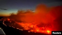 FILE - The Parker Lake wildfire glows in a photograph taken by a B.C. Emergency Health Services crew member through the window of an airplane evacuating patients from nearby Fort Nelson, British Columbia, Canada, May 10, 2024. 