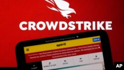 The logo for CrowdStrike and a Spirit Airlines webpage are shown on a computer screen and mobile phone screen, in New York, July 19, 2024. 