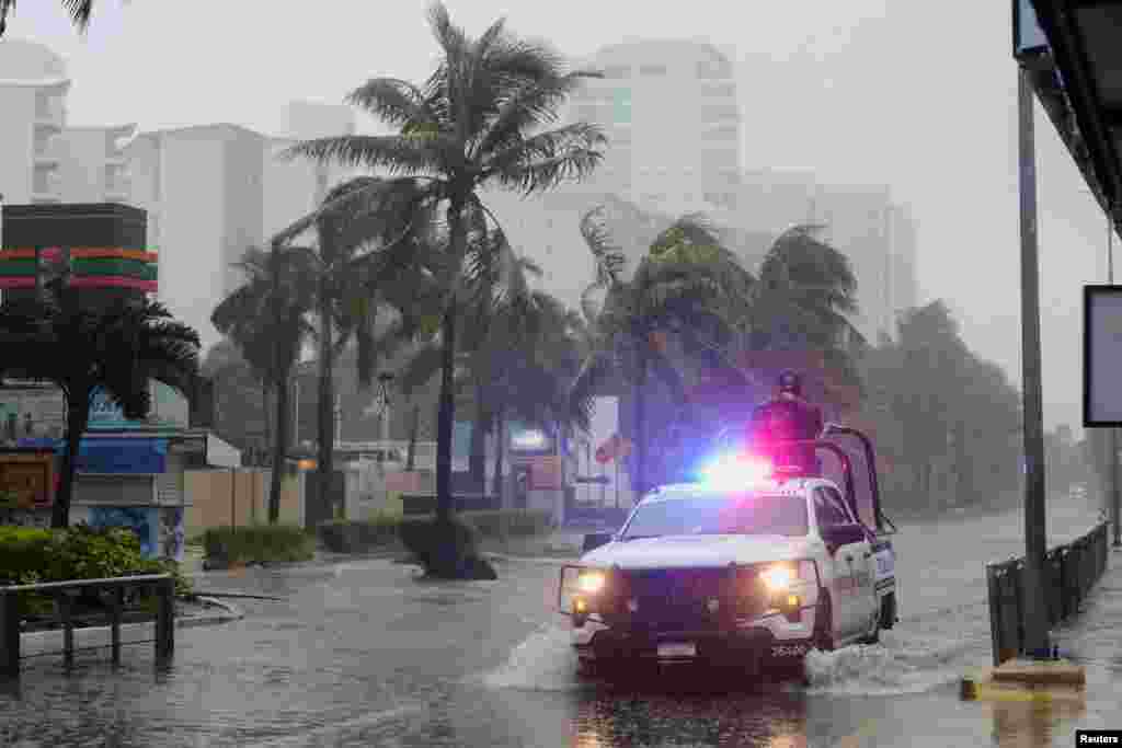 Miembros de la Guardia Nacional patrullan por una calle inundada durante los fuertes vientos y lluvias causados por el huracán Beryl, en Cancún, México.