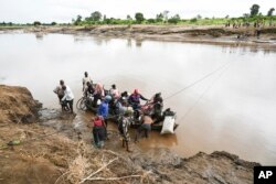 Men transport their salvaged belongings in Chiradzulu, southern Malawi, Friday March 17, 2023.