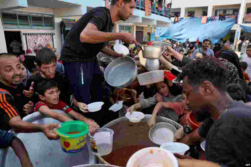 Palestinian children receive food at a U.N.-run school in Rafah, on the southern Gaza Strip amid ongoing battles between Israel and Hamas militants.