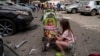 Children wait near the site of Okhmatdyt children’s hospital hit by Russian missiles, in Kyiv, Ukraine, Monday, July 8, 2024