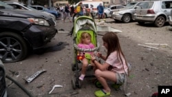 Children wait near the site of Okhmatdyt children’s hospital hit by Russian missiles, in Kyiv, Ukraine, Monday, July 8, 2024