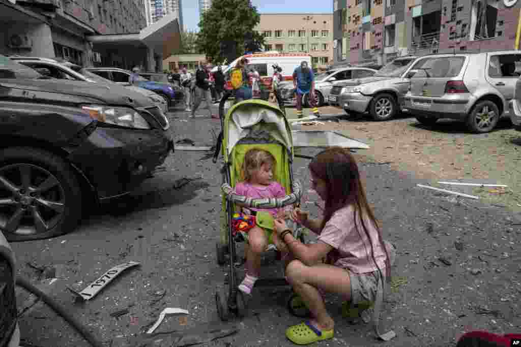 Dos niñas esperan cerca del hospital infantil alcanzado por los ataques aéreos de Rusia en Kiev, Ucrania, el lunes 8 de julio de 2024. (Foto AP/Evgeniy Maloletka)