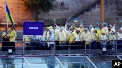 Ukraine's athletes wave Ukrainian flags aboard a boat as it makes its way along the Seine river in Paris, France, during the opening ceremony for the 2024 Summer Olympics, July 26, 2024. 