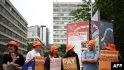 Sejumlah tenaga medis berdemo sambil membawa poster-poster Asosiasi Medis Inggris di London, 27 Juni 2024. (Foto: Henry Nicholls/AFP)