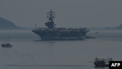 A fishing boat (R) sails past the USS Ronald Reagan, a U.S. Navy Nimitz-class nuclear-powered aircraft carrier, in Danang, Vietnam, June 25, 2023. 